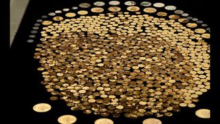 We see hundreds of gold and silver coins against a black background.