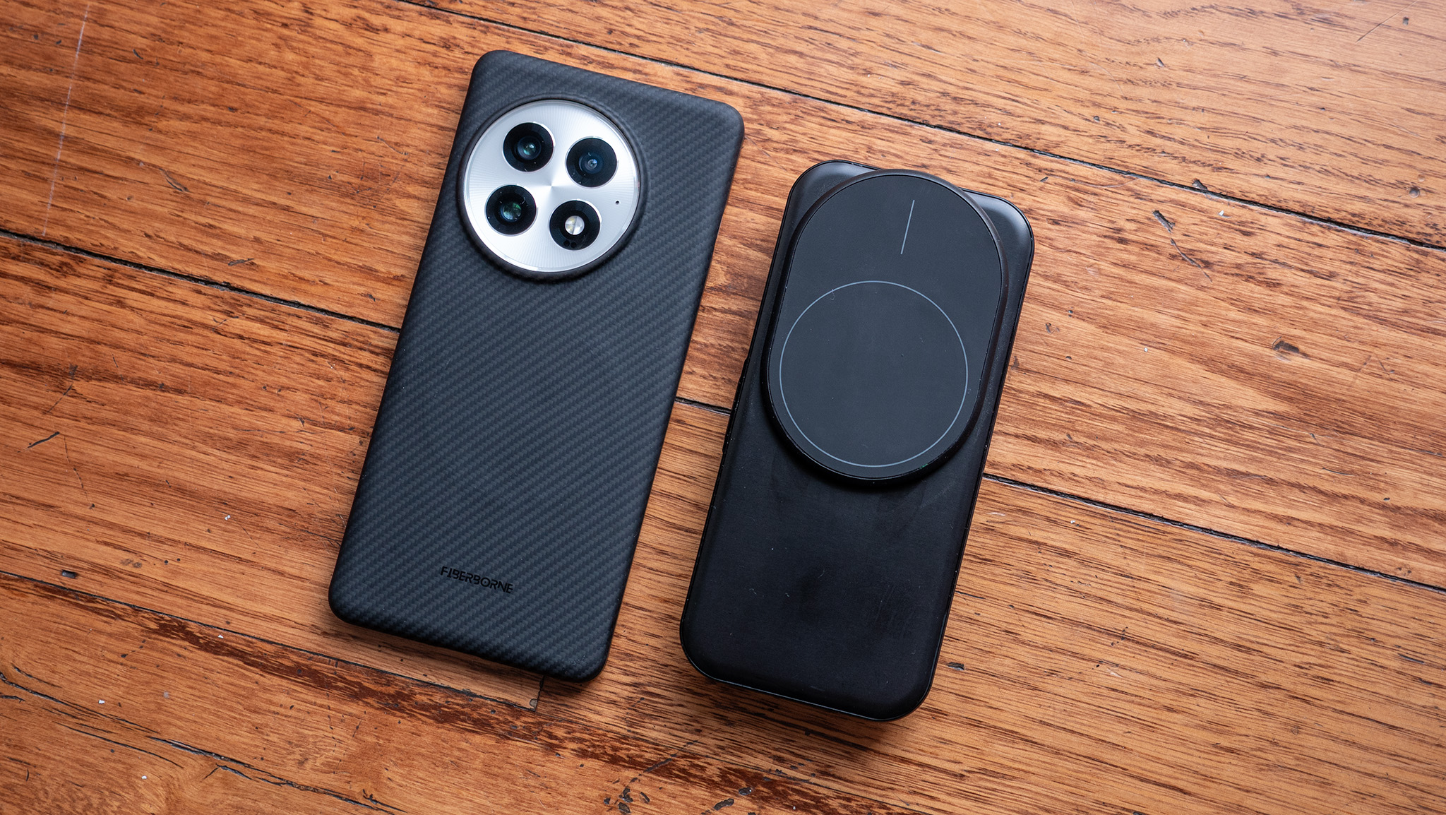 An Ohsnap MCON controller is closed and placed next to a OnePlus 13 wearing a Thinborne case to show its diminutive size