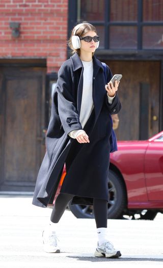 Kaia Gerber wearing a long coat, black leggings, and Nike V2K sneakers in New York