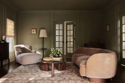 A dark green walled room with pink sofas