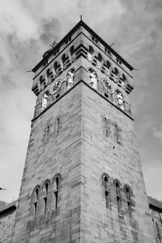 A black and white photograph of one of Cardiff Castle's towers with a slightly cloudy sky above.