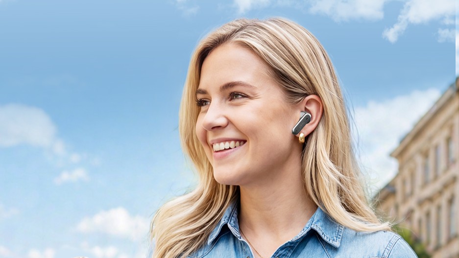 Tribit FlyBuds 3 earbuds worn by a lady with a sunny blue sky background