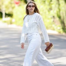 Sofia Richie wears a white sweater, white jeans, and white sneakers.