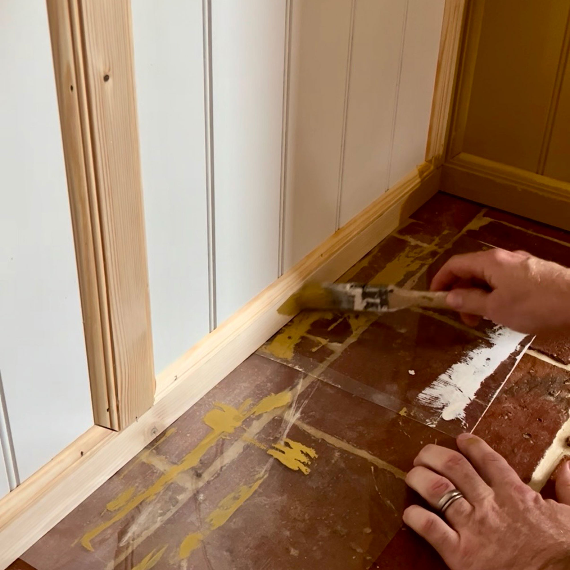 Man painting wooden trim underneath panelling