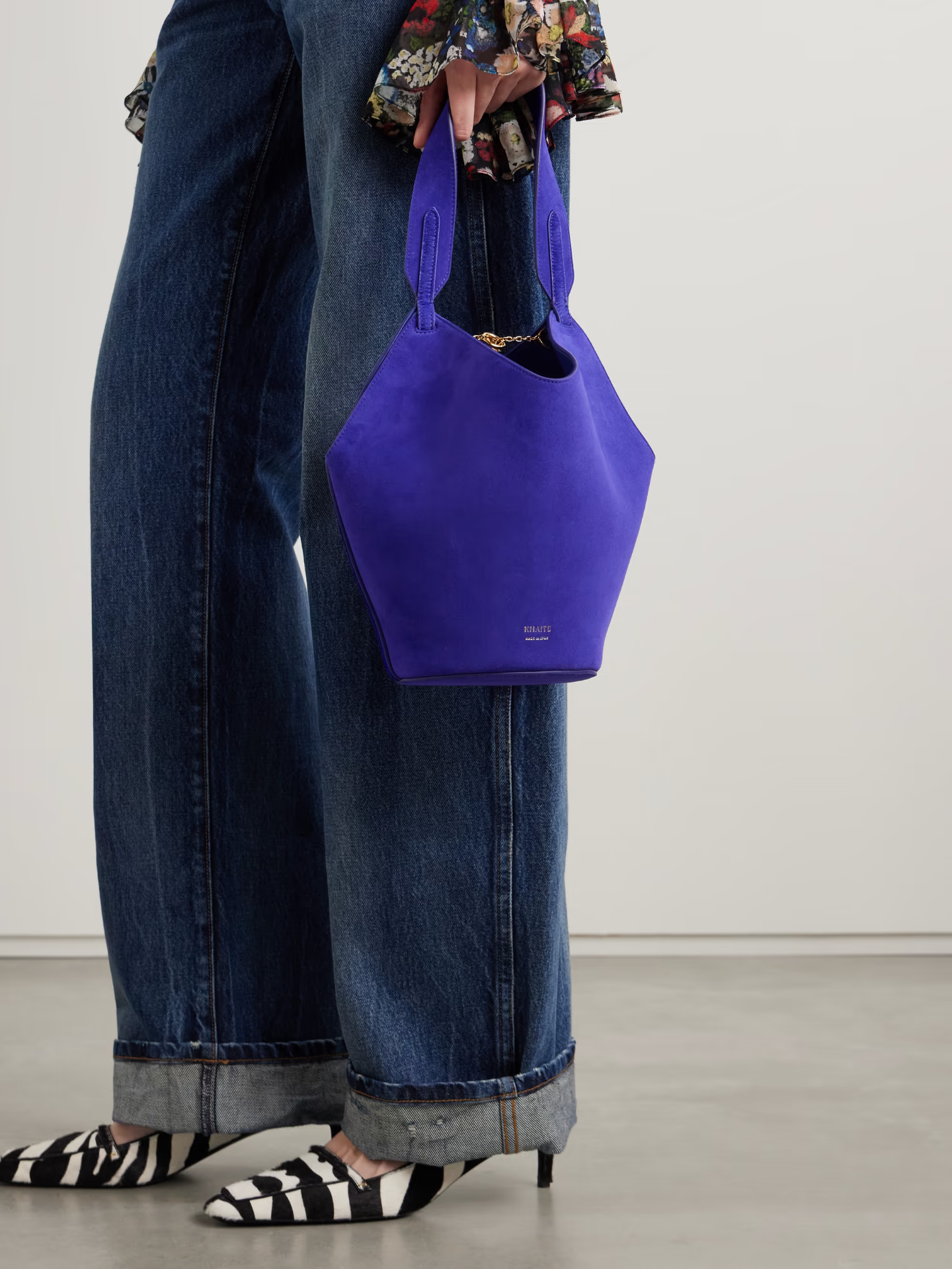 A model holding a suede purple bucket bag.