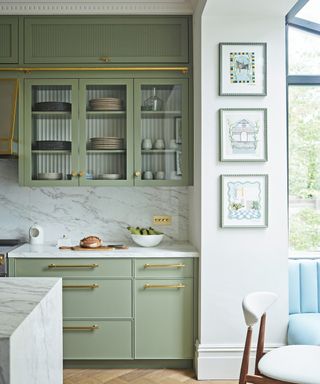 green kitchen with glass fronted fluted cabinets and marble splashback and worksurfaces
