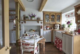 Kitchen with wooden cabinets, butlers sink, wooden table and chairs and red details