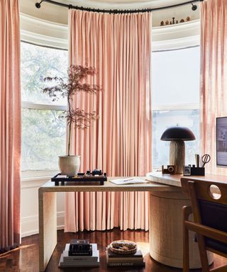 Home office in window corner with long pink curtains