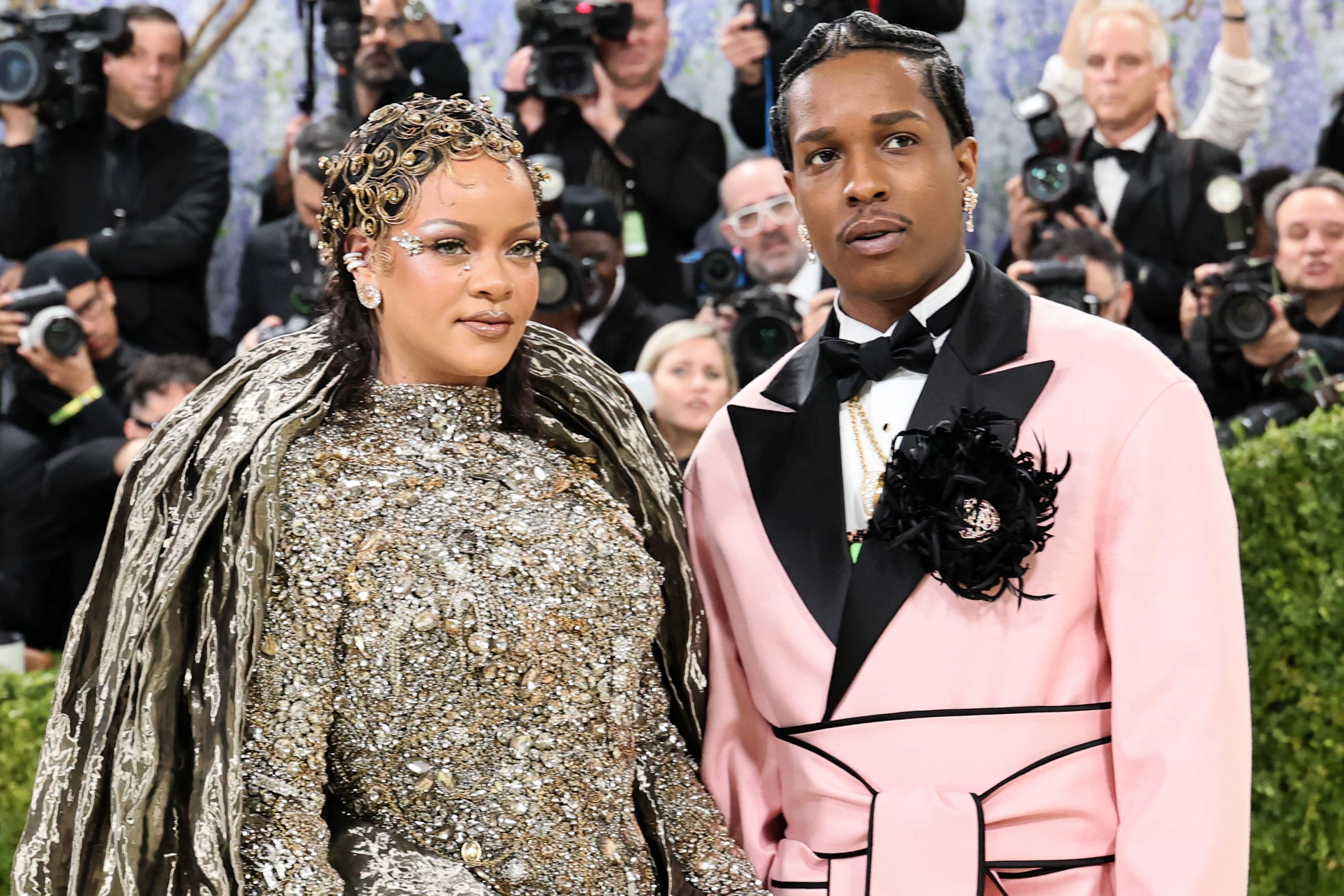 a man and a woman at the met gala in golden makeup and a pink suit