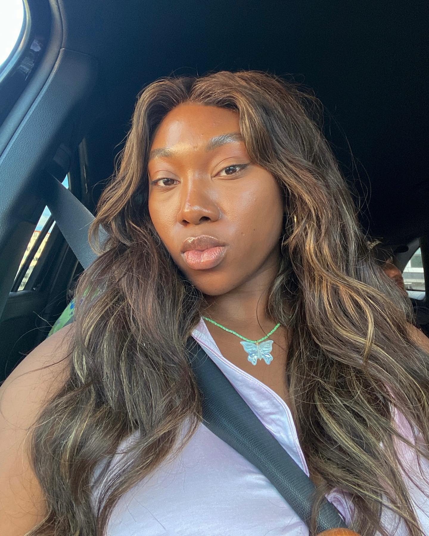 Une femme prenant un selfie dans la voiture avec des cheveux bruns usés
