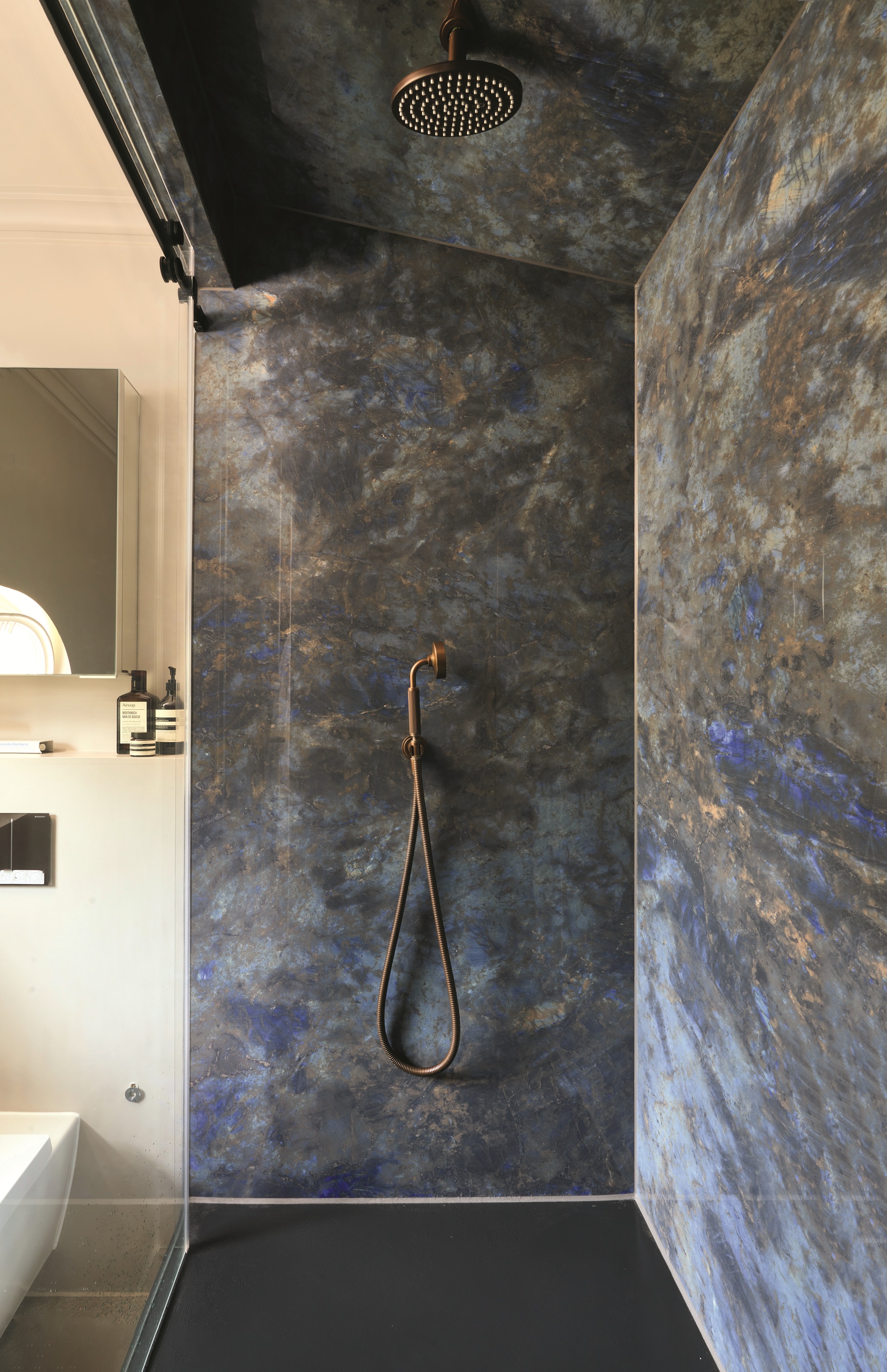 a dark black and blue shower in an otherwise light bathroom