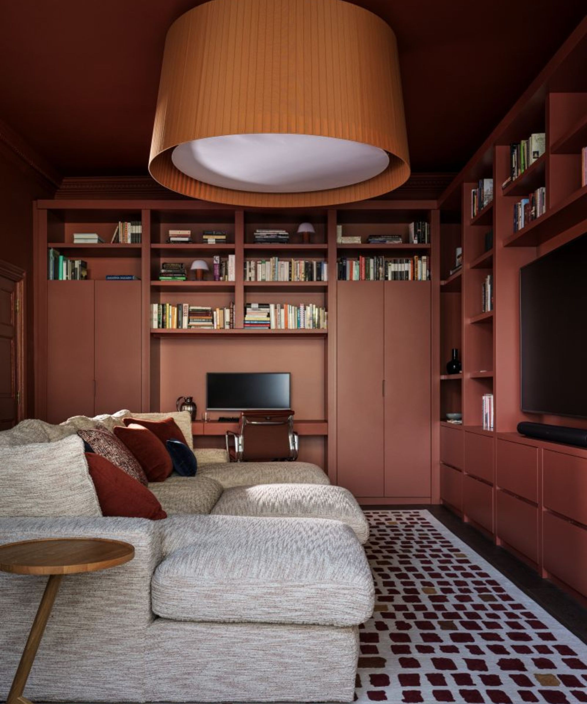 Snug room with sectional sofa, geometric rug and built-in shelving painted in burgundy