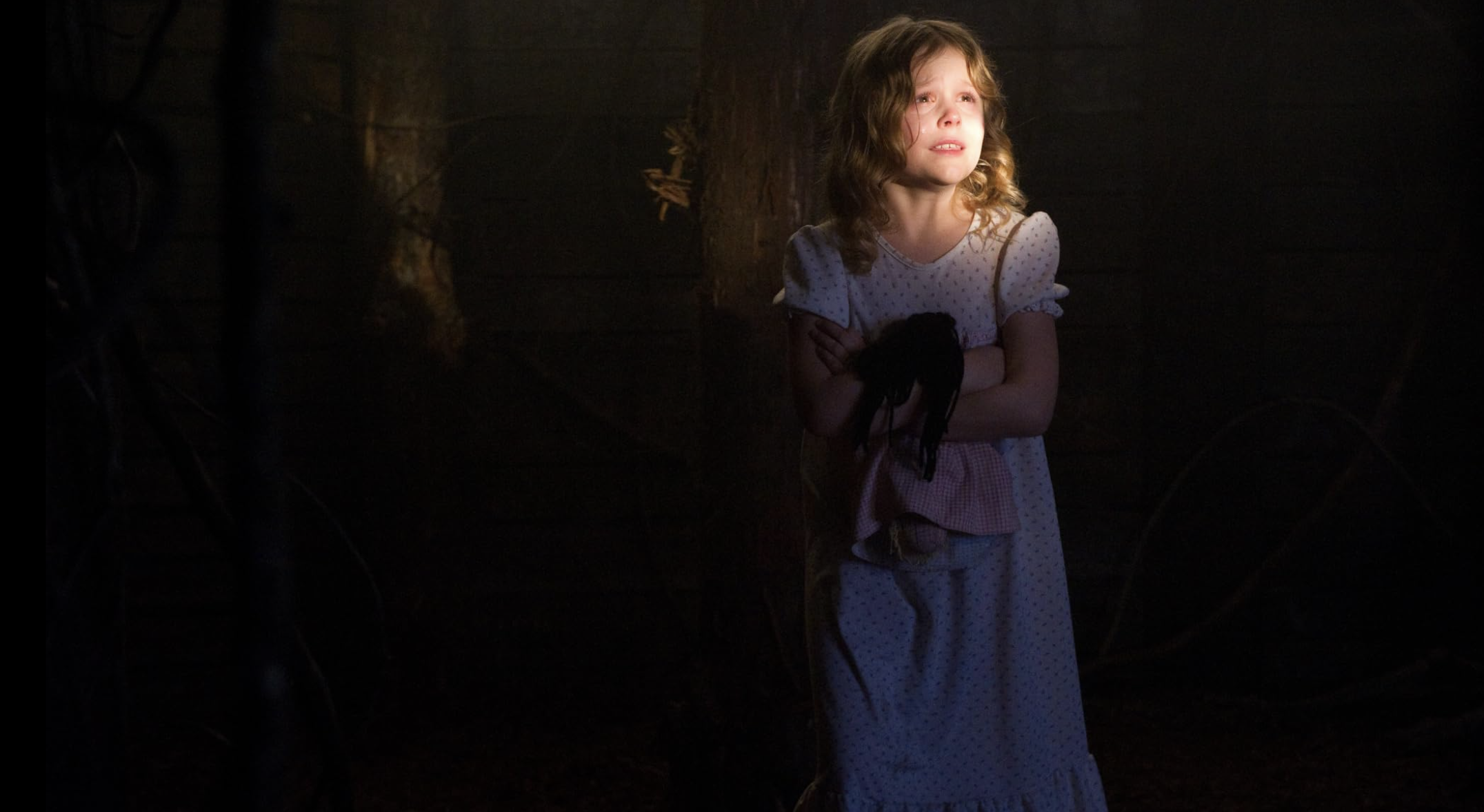 A child looks scared and clutches a doll