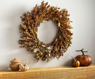 A Evergreen Bunny Tail Grass Boxwood Wreath above a mantel decorated with pumpkins