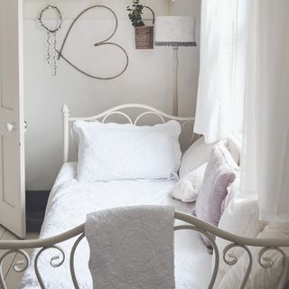 Single bed with ornate metal headboard and pillows
