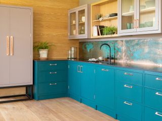 Small kitchen with teal kitchen cabinets and wood walls by Naked Kitchens
