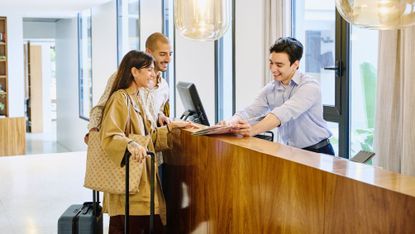 Smiling couple and hotel concierge looking at map
