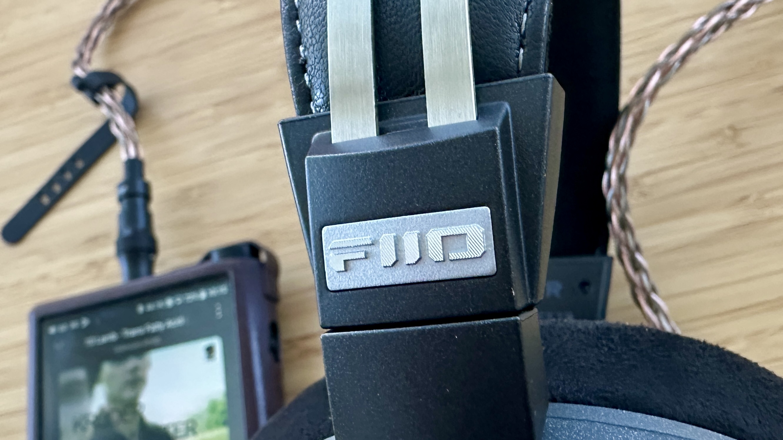 Closeup up of the adjustable headband of the FiiO FT13 closed-back over-ear wired headphones, on a wooden surface.