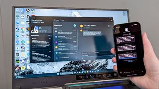 iPhone 16 in hand being held in front of Asus ROG Strix 17 display showing Phone Link app messaging feature
