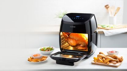 Tower 10-in-1 Air Fryer Xpress Pro Combo on white kitchen countertop with whole chicken cooking