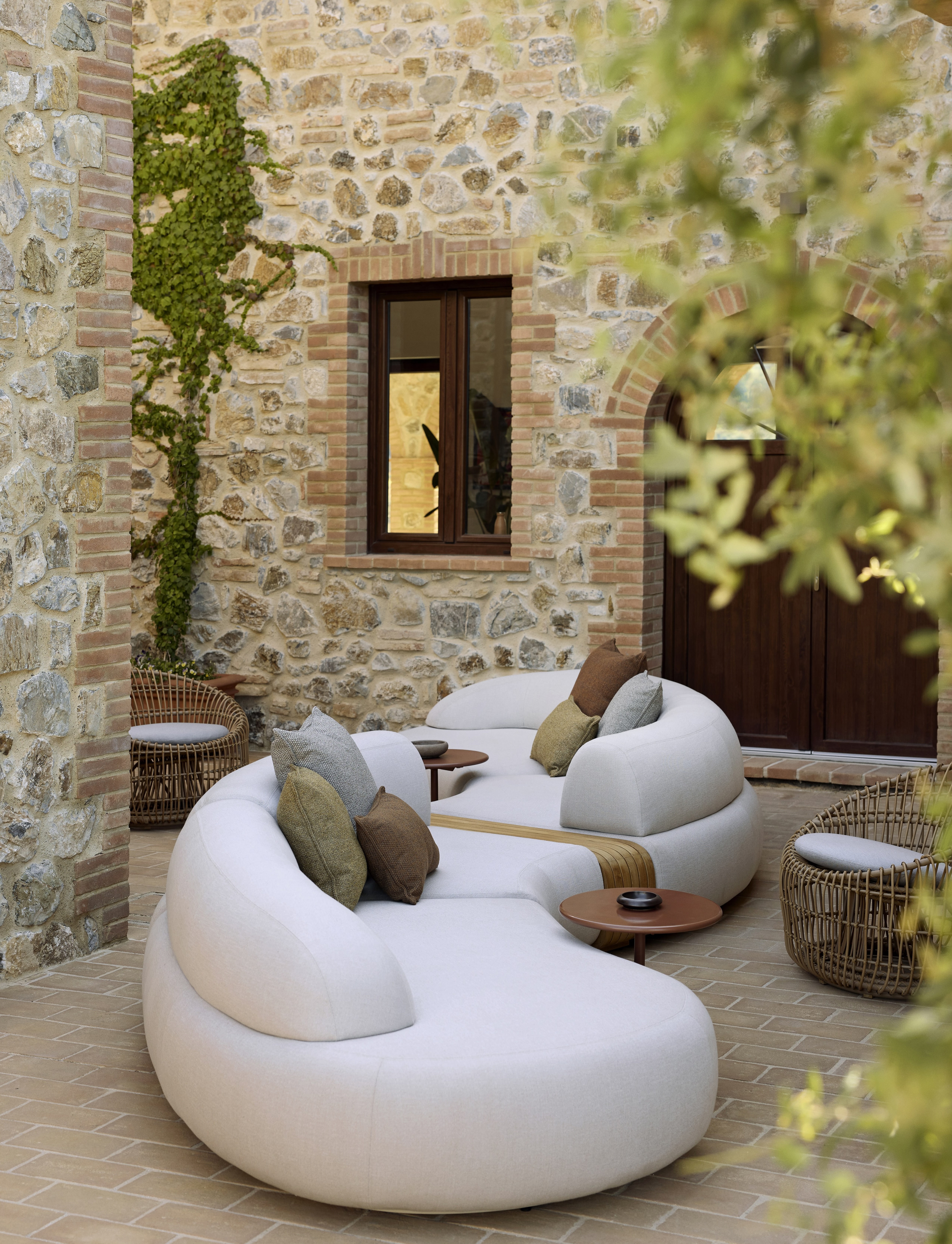 A curved outdoor sofa with rattan armchairs