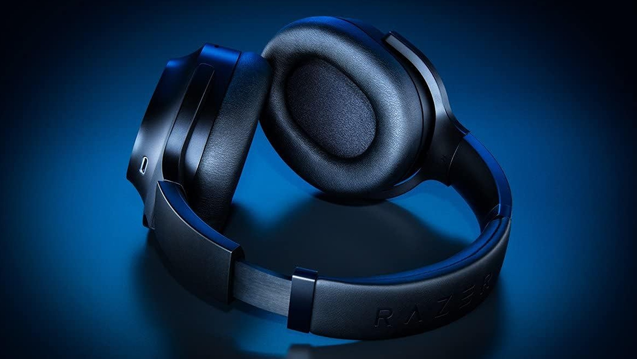 A pair of stylish black over-ear headphones with padded ear cups, set against a soft gradient blue background, giving off a modern, techy feel.