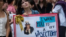 Protester holding a sign saying I want you to get a vasectomy