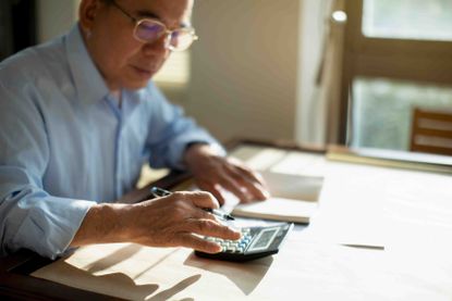 A ma at a desk with papers and a calculator