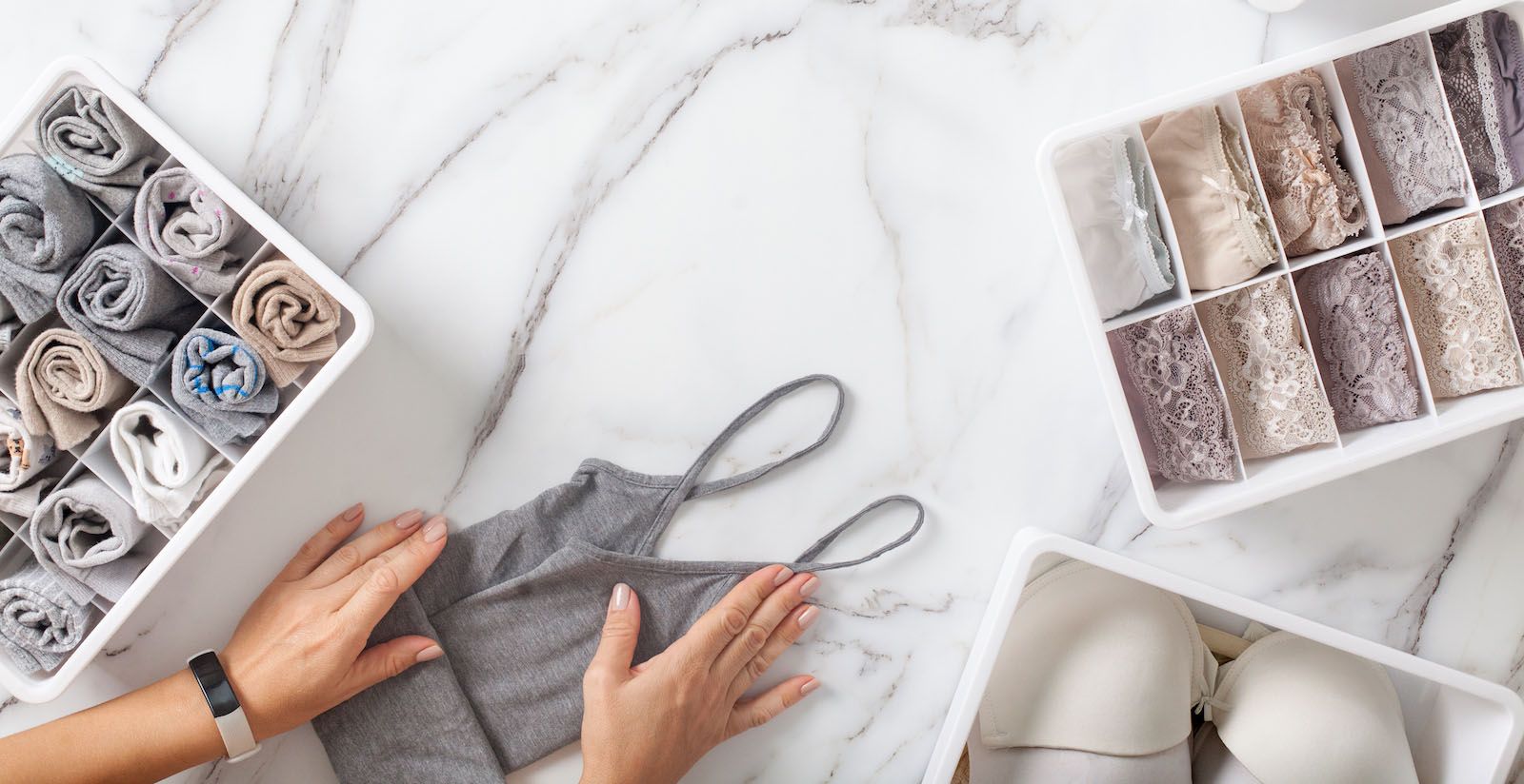 person organizing clothing into groups to store in baskets together to demonstrated the suggested home organization idea