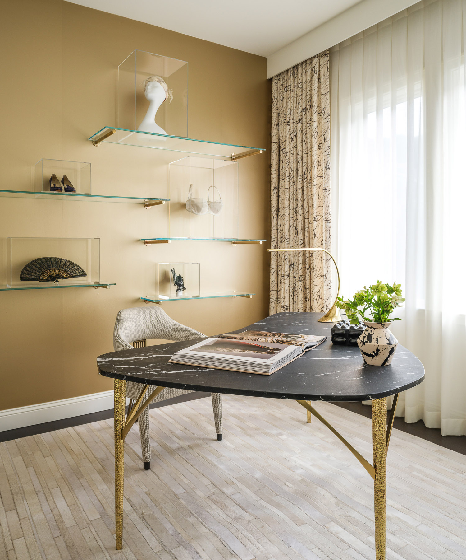 home office with beige wall, large rounded black desk and white armchair