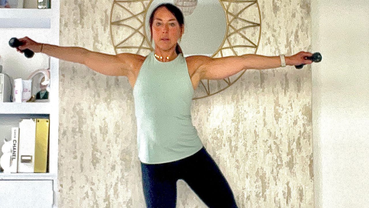 Lucy Miller performing dumbbell lateral raise with side leg lift at home