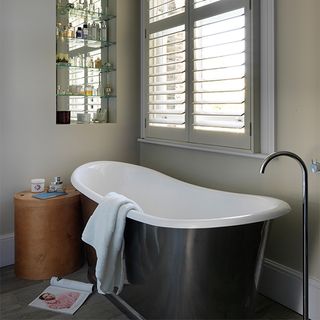 bathroom with bathtub cream colour wall window and shelf