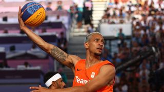 Worthy de Jong of Team Netherlands performs a hook shot at the 3x3 basketball at the 2024 Paris Olympic Games in an orange vest.