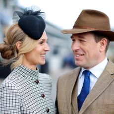 Harriet Sperling and Peter Phillips smiling at each other at Cheltenham races wearing hats