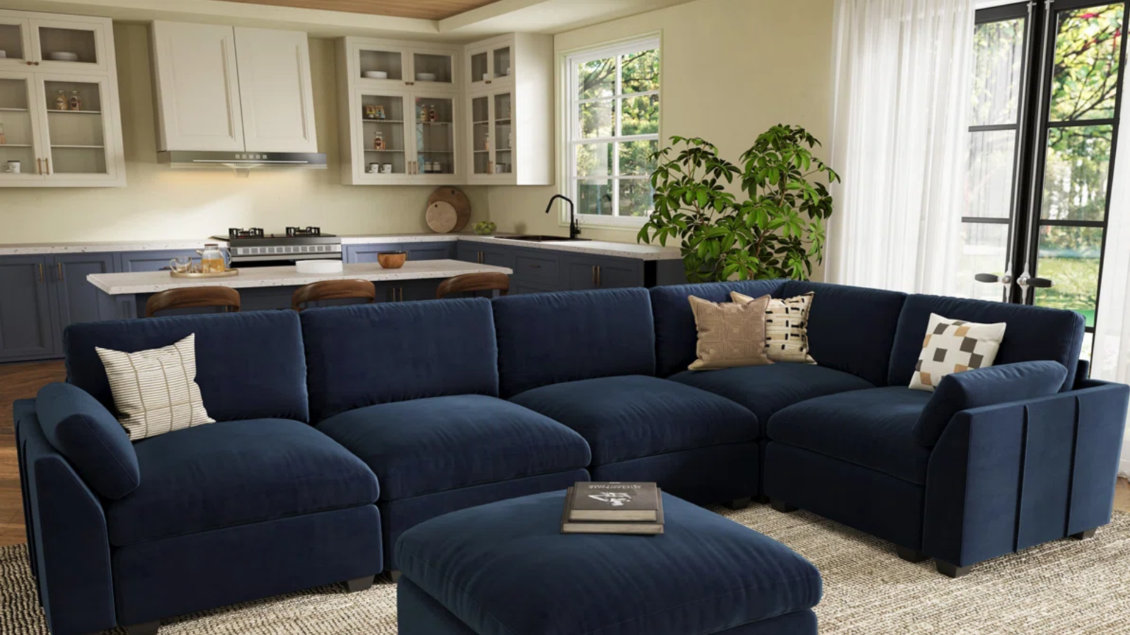 a living room with a large blue sectional with a few pillows on top in front of an open concept kitchen