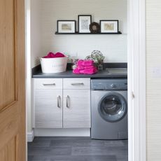 Laundry room with grey washing machine and pink towels on grey counter