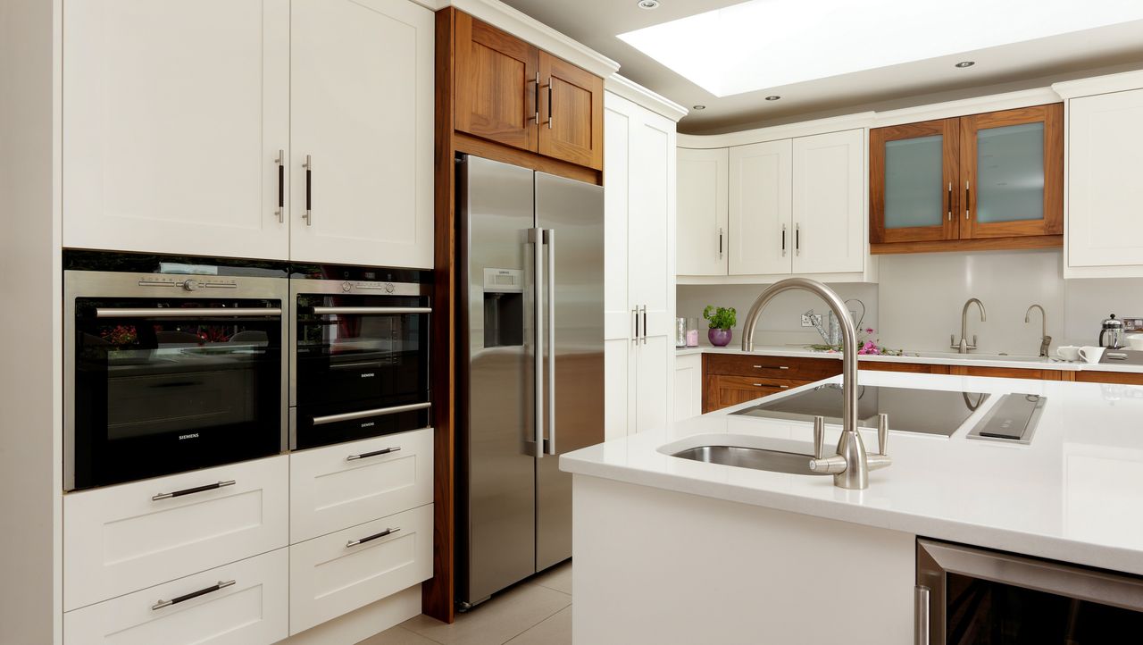 A kitchen with a central island and American style fridge freezer