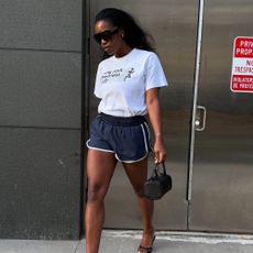Influencer @nlmarilyn wears a white t-shirt tucked into sports shorts with heeled sandals.