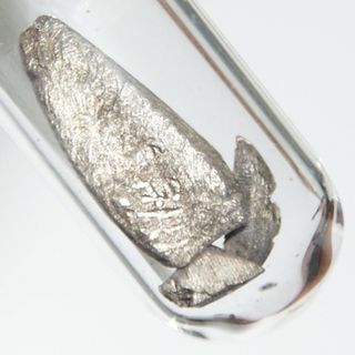 Weakly oxidized europium, hence slightly yellowish. 1.5 grams, large piece 0.6 x 1.6 cm.
