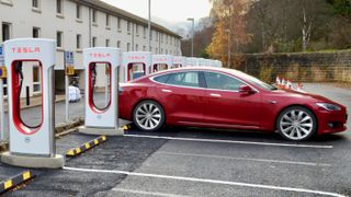 A red Tesla Model S parked at a Tesla Supercharger
