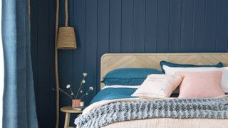 navy blue painted bedroom with wood bed and blush pink bedding