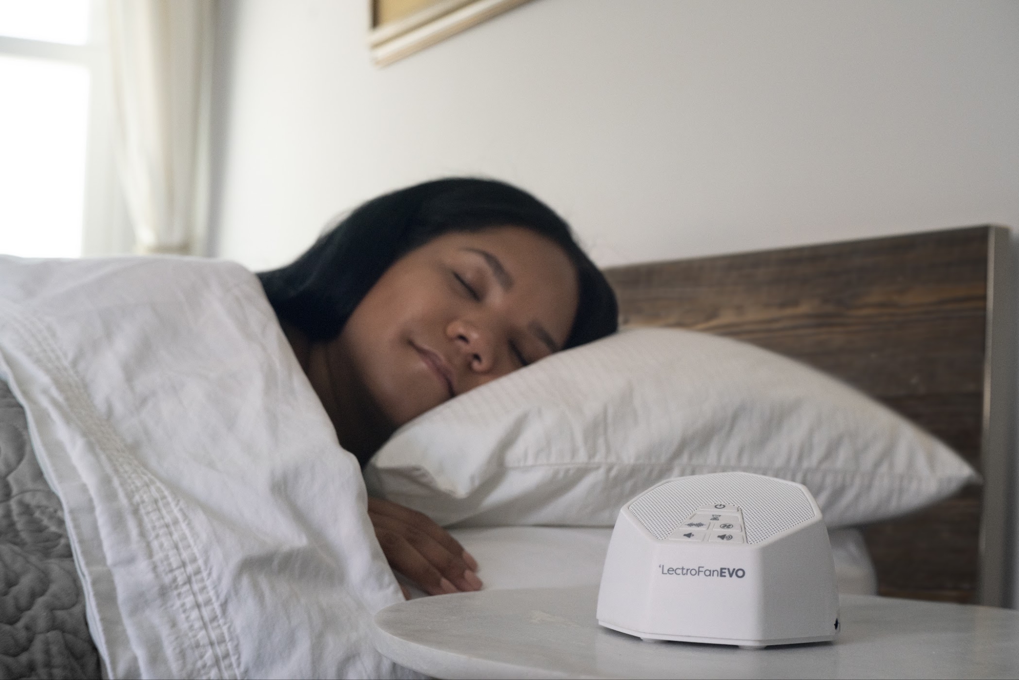 A woman sleeps next to her LectroFan EVO
