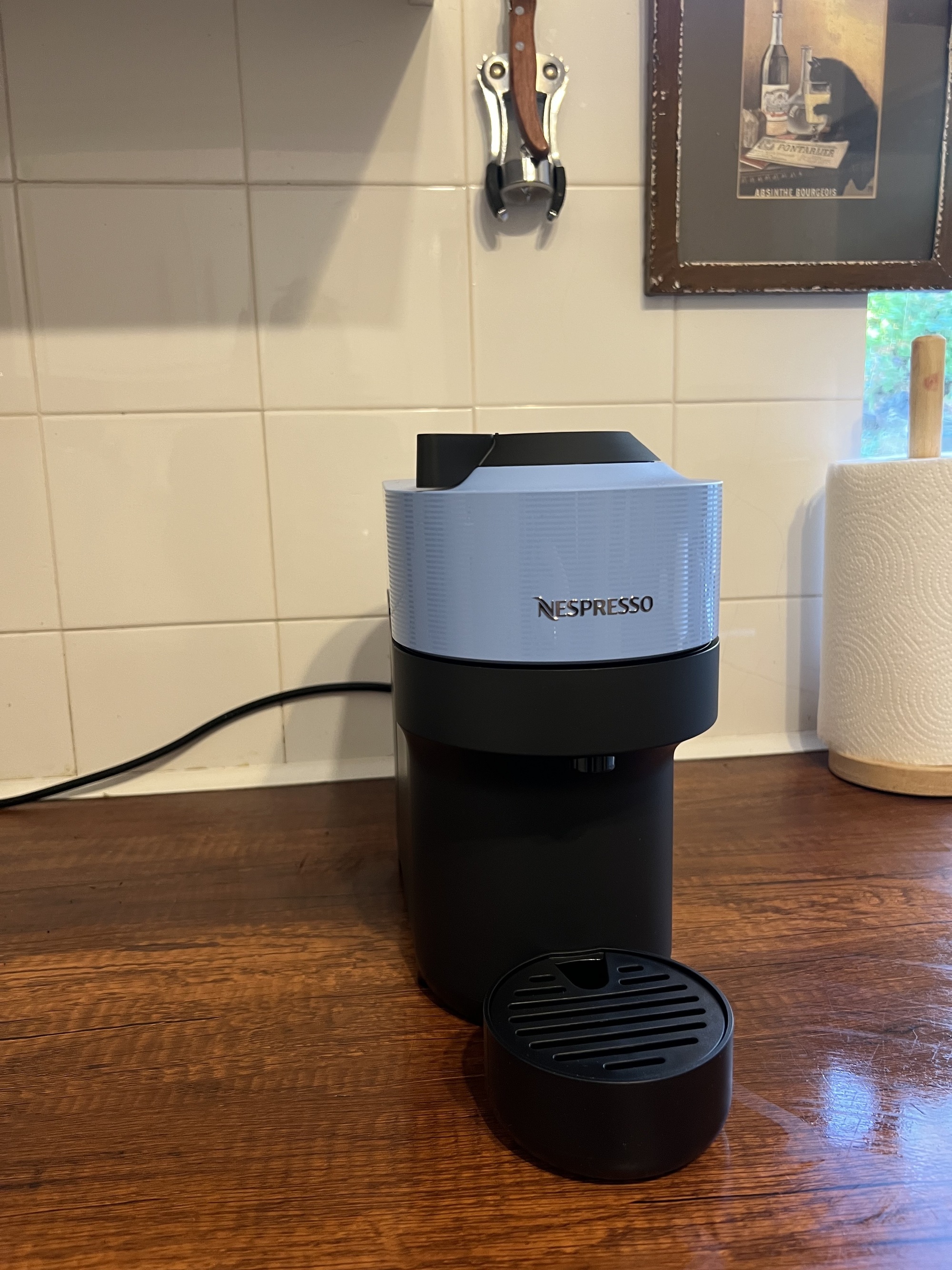 Image of a Nespresso pod coffee machine that is blue and black on a wooden counter