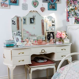 dressing room with pink wall and table and stool with mirror
