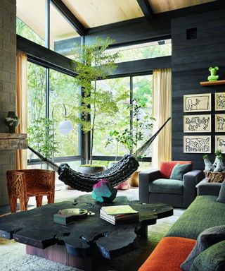living room with black cedar walls, hammock, wooden coffee table and gray and orange chairs and sofa