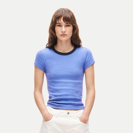 a woman wearing a blue ringer t-shirt and white shorts