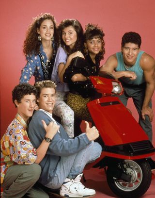 a promo shot of saved by the bell of the high schoolers standing around a red scooter