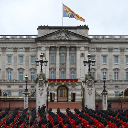 The exterior of Buckingham Palace with a row of red uniformed guards outside