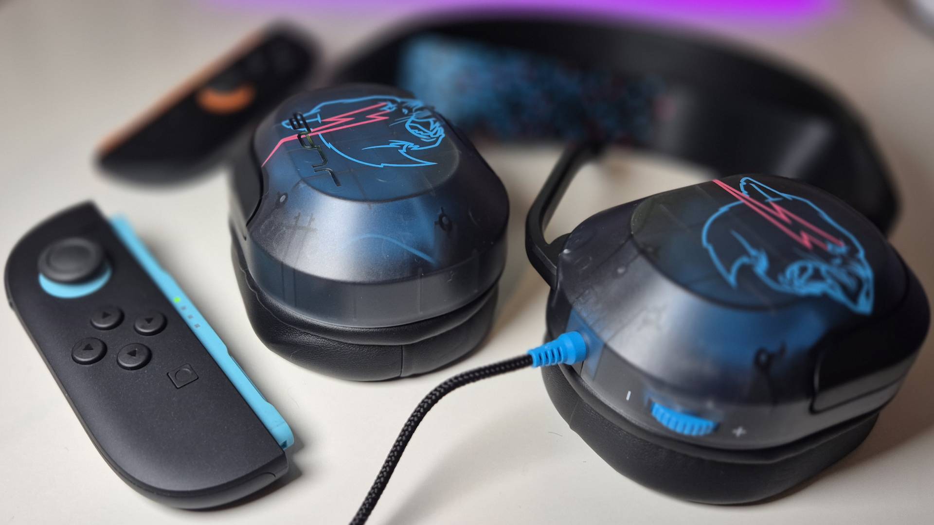 Photo by Rosalie Newcombe of the JLab Gaming x MrBeast Nightfall wired headset sitting next to a Joy-Con 2 controller.