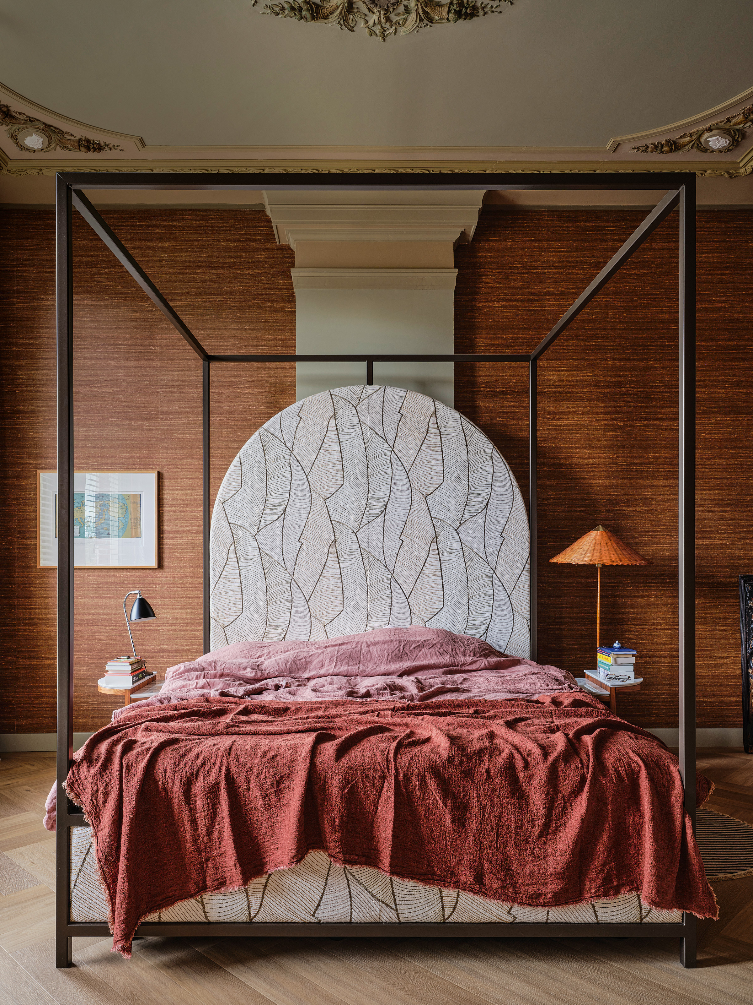 Bed with rust wallpaper, oversized leaf pattern headboard and rust and pink bedding